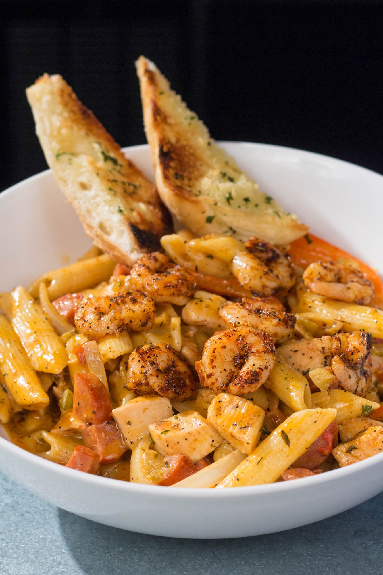 Blackened shrimp, chicken breast, and andouille sausage with onions & peppers tossed in our homemade cajun cream sauce, served with toasted garlic bread