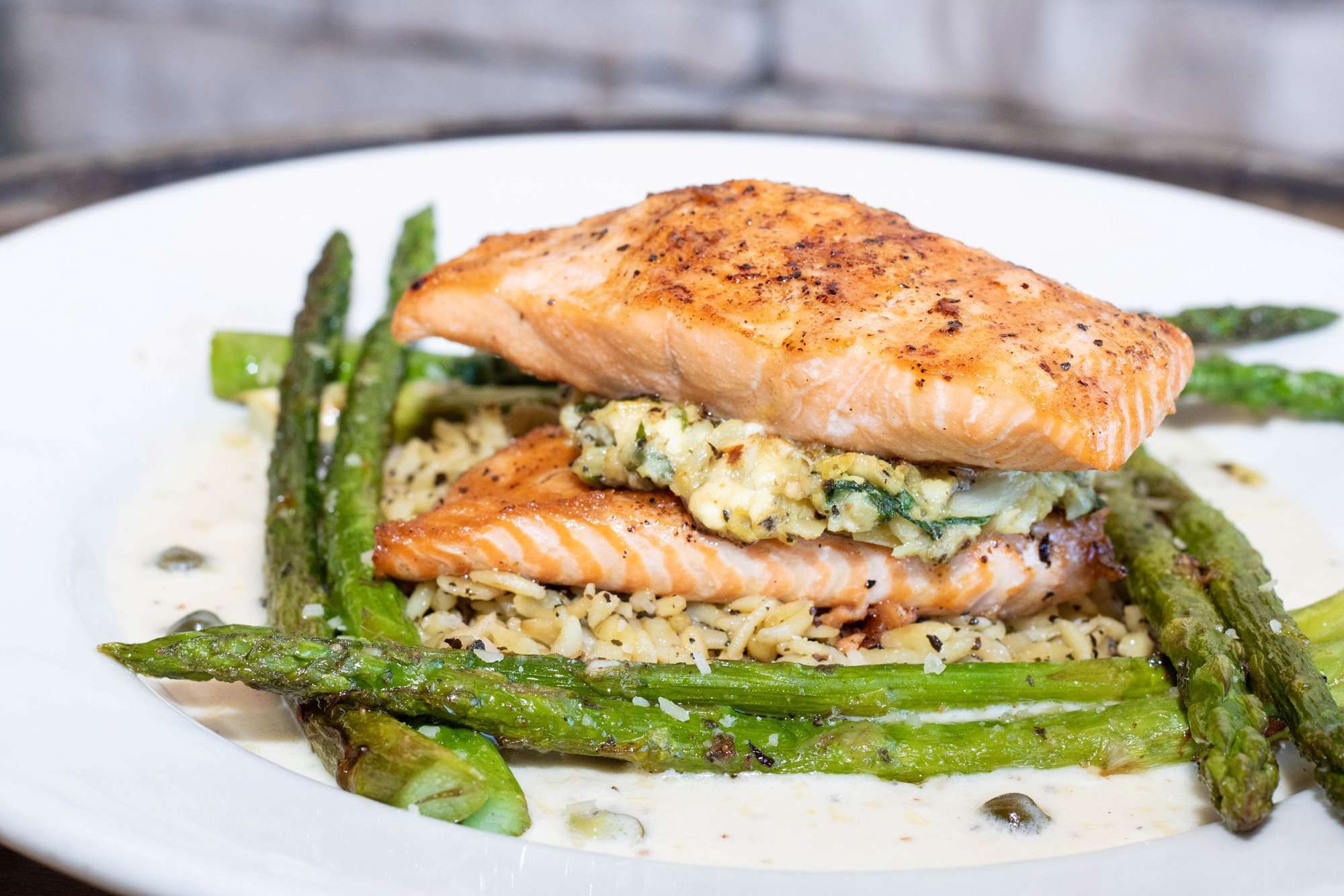 North Atlantic salmon stuffed with lump crab meat, spinach, artichokes, and feta. Served with a side of sauteed asparagus, herbed orzo pasta, and our white wine basil lemon butter.