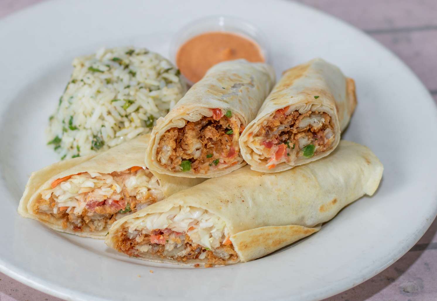 Fried Alaskan pollock or shrimp, ancho aioli, cabbage, cheddar-jack and pico rolled in flour tortillas with cilantro lime rice