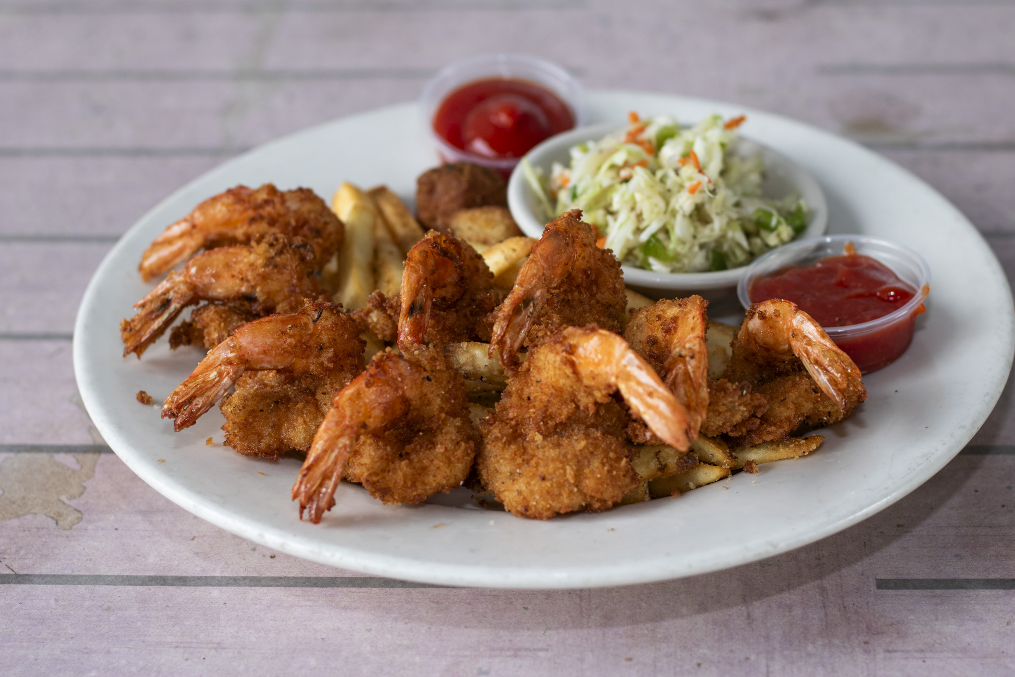 Ten large shrimp hand breaded with seasoned panko and deep fried. Served with crispy french fries, apple cider slaw, and our jalapeno hush puppies