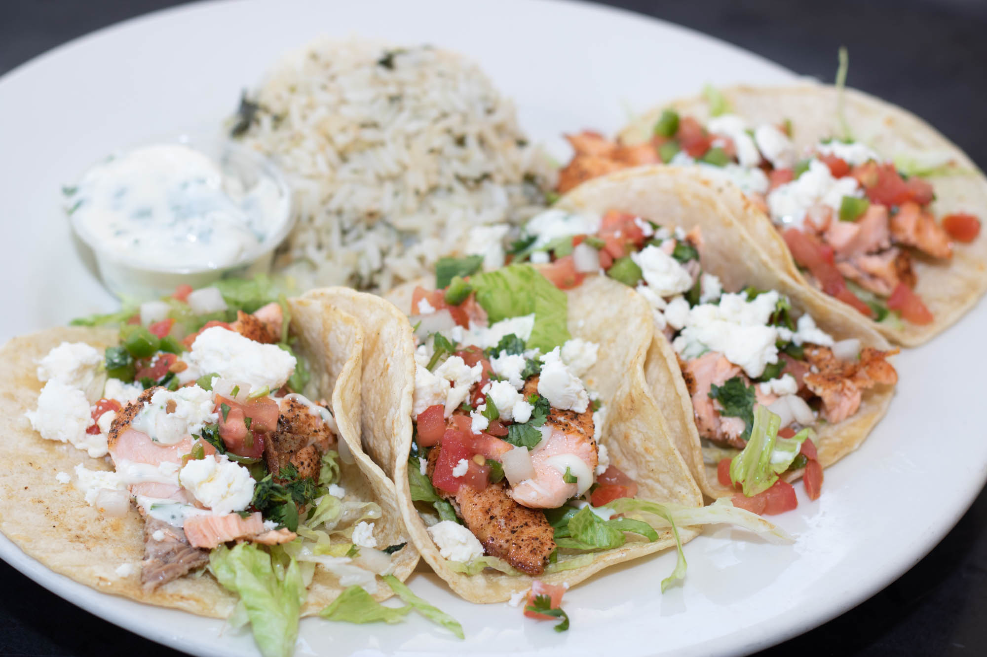 North Atlantic salmon, blackened and served on warm soft corn tortillas with shredded lettuce, cilantro lime aioli, feta, and pico de gallo with a side of cilantro lime rice.